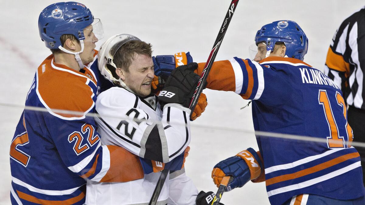 Kings forward Trevor Lewis, center, is punched by Edmonton Oilers forward Rob Klinkhammer while being held by defenseman Keith Aulie during the second period of the Kings' 4-2 loss Tuesday.