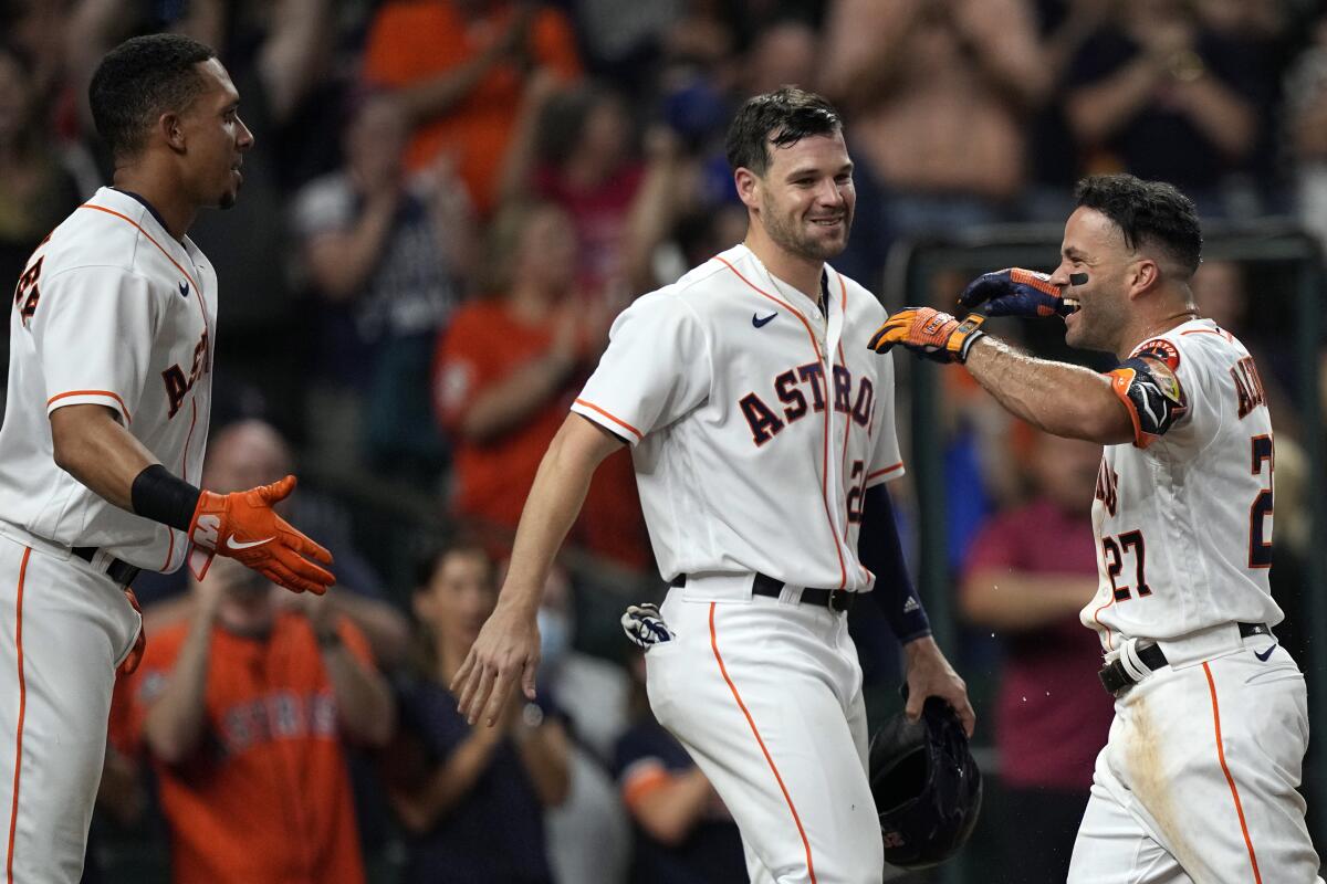 Houston Astros' Jose Altuve (27) celebrates with Chas McCormick (20) and Michael Brantley after hitting a game-winning grand slam during the 10th inning of a baseball game against the Texas Rangers Tuesday, June 15, 2021, in Houston. The Astros won 6-3. (AP Photo/David J. Phillip)