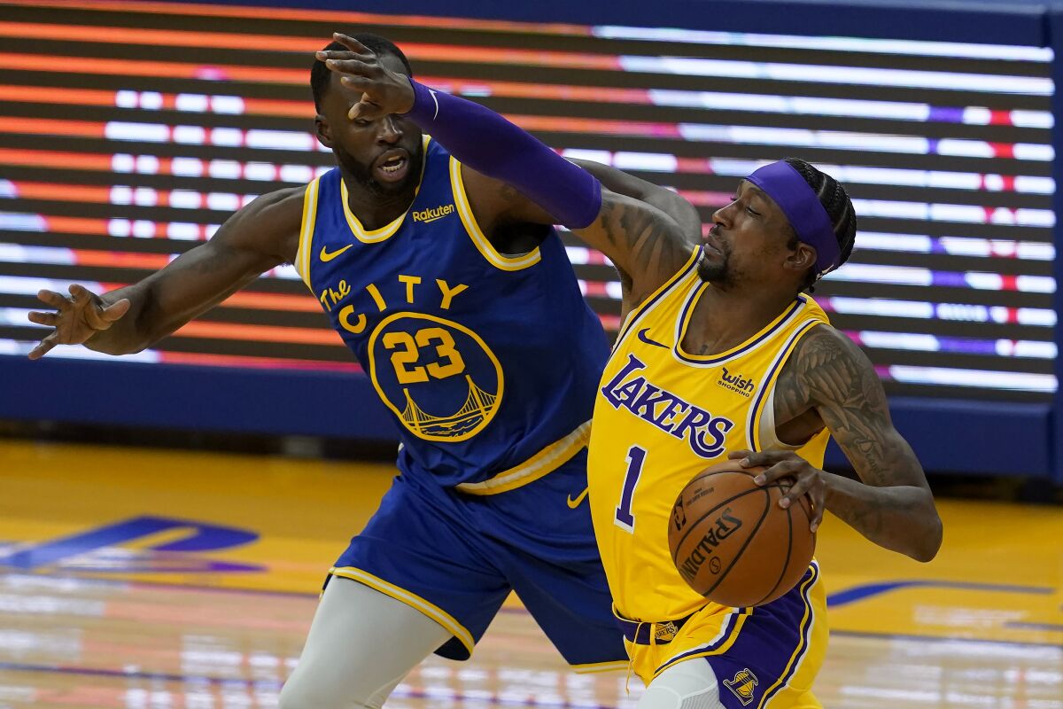 Lakers guard Kentavious Caldwell-Pope is defended by Golden State Warriors forward Draymond Green.
