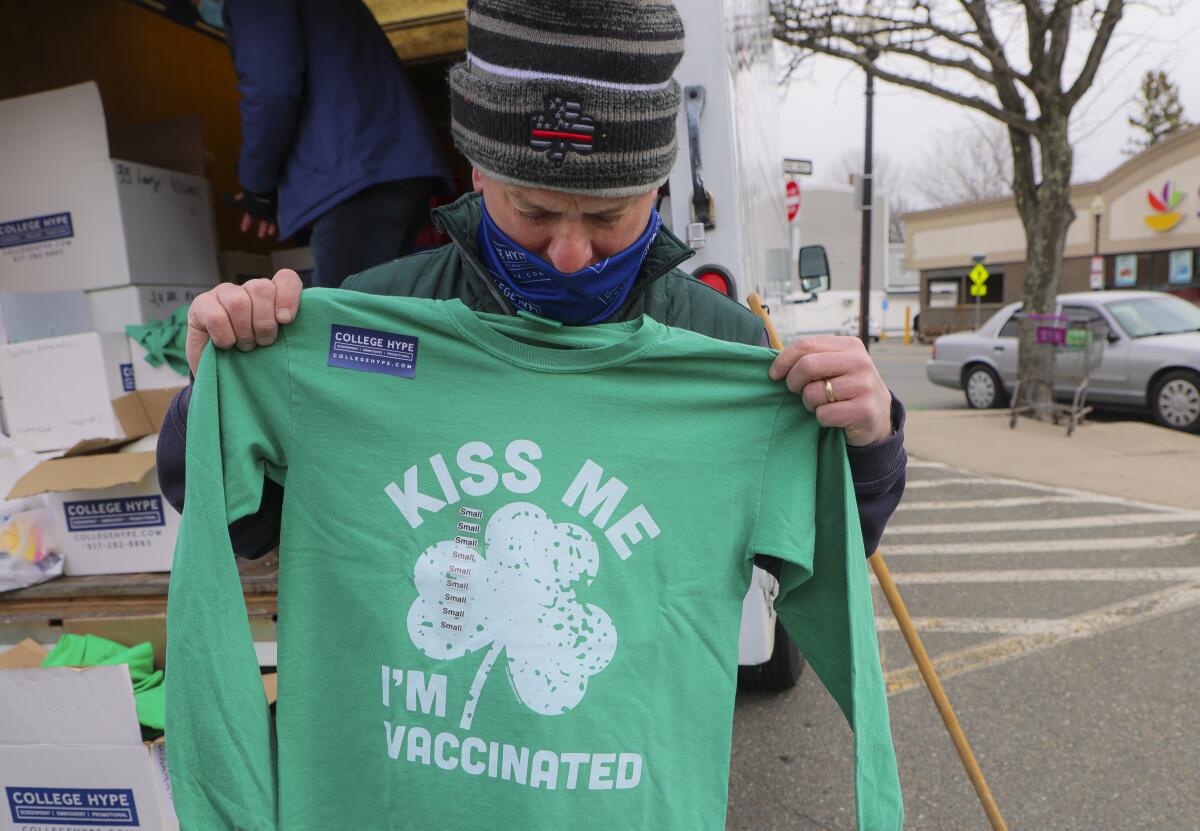 A green T-shirt says 'Kiss me, I'm vaccinated'