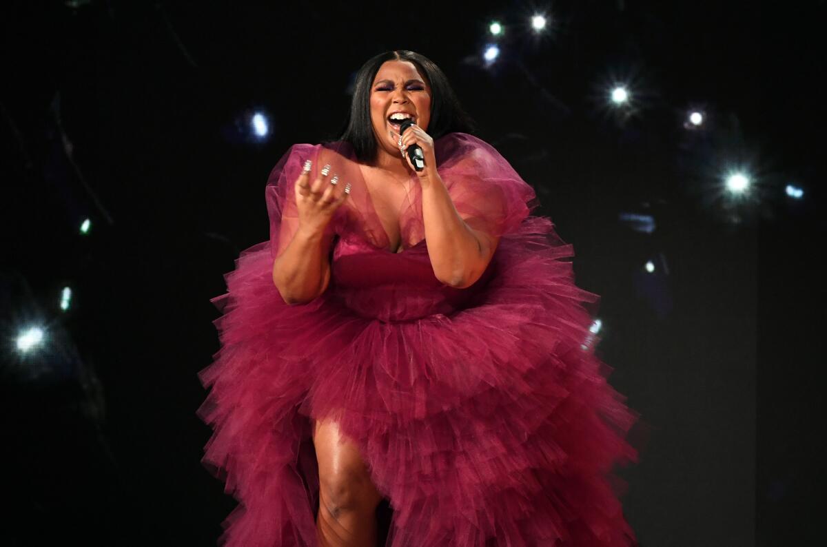 A woman in a tulle dress sings into a microphone