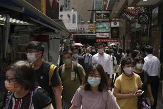 People wearing face masks walk along a side street in Mongkok, a shopping district of Hong Kong, Monday, Aug. 8, 2022. Hong Kong will reduce the mandatory hotel quarantine for overseas arrivals to three days from a week, the city's leader said Monday. (AP Photo/Kin Cheung)