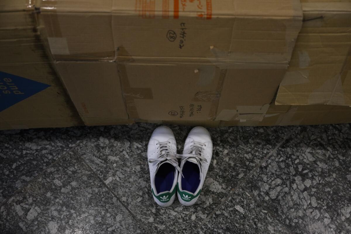 Homeless person's shoes are placed in front of a cardboard box at Shinjuku Station Tuesday, Jan. 7, 2020, in Tokyo. Dozens of homeless people sleeping rough in shuttered Tokyo subway stations worry that with Japan's image at stake authorities will force them to move ahead of the Olympics. (AP Photo/Jae C. Hong)