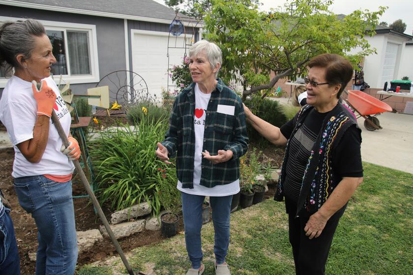 Homeowner Mary Parpal, center, says "this is a blessing for me" as group of volunteers from Labor of Love, take part in a landscaping makeover for this Costa Mesa homeowner, organized by Love Costa Mesa Neighborhood Initiative the event took place at 930 Oak street in Costa Mesa on Saturday, April 2, 2022. (Photo by James Carbone)