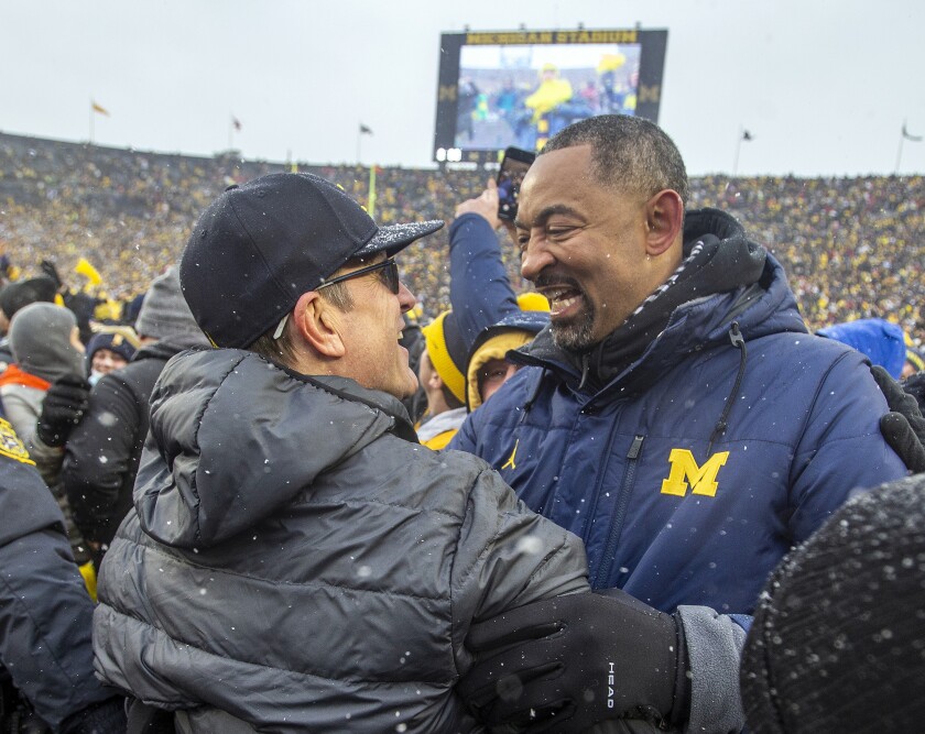 Michigan football coach Jim Harbaugh, left, is congratulated by Wolverines basketball coach Juwan Howard on Nov. 27, 2021.