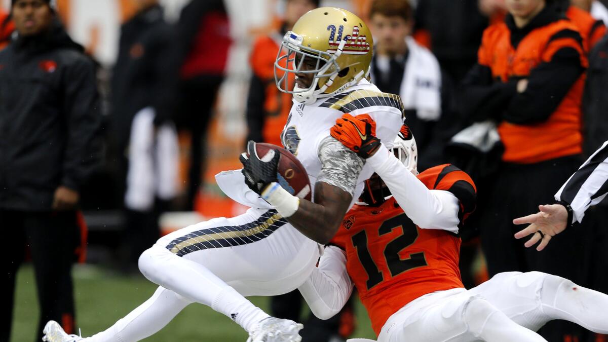 UCLA receiver Kenneth Walker is tackled by Oregon State defensive back Kendall Hill after making a reception in the first half Saturday.