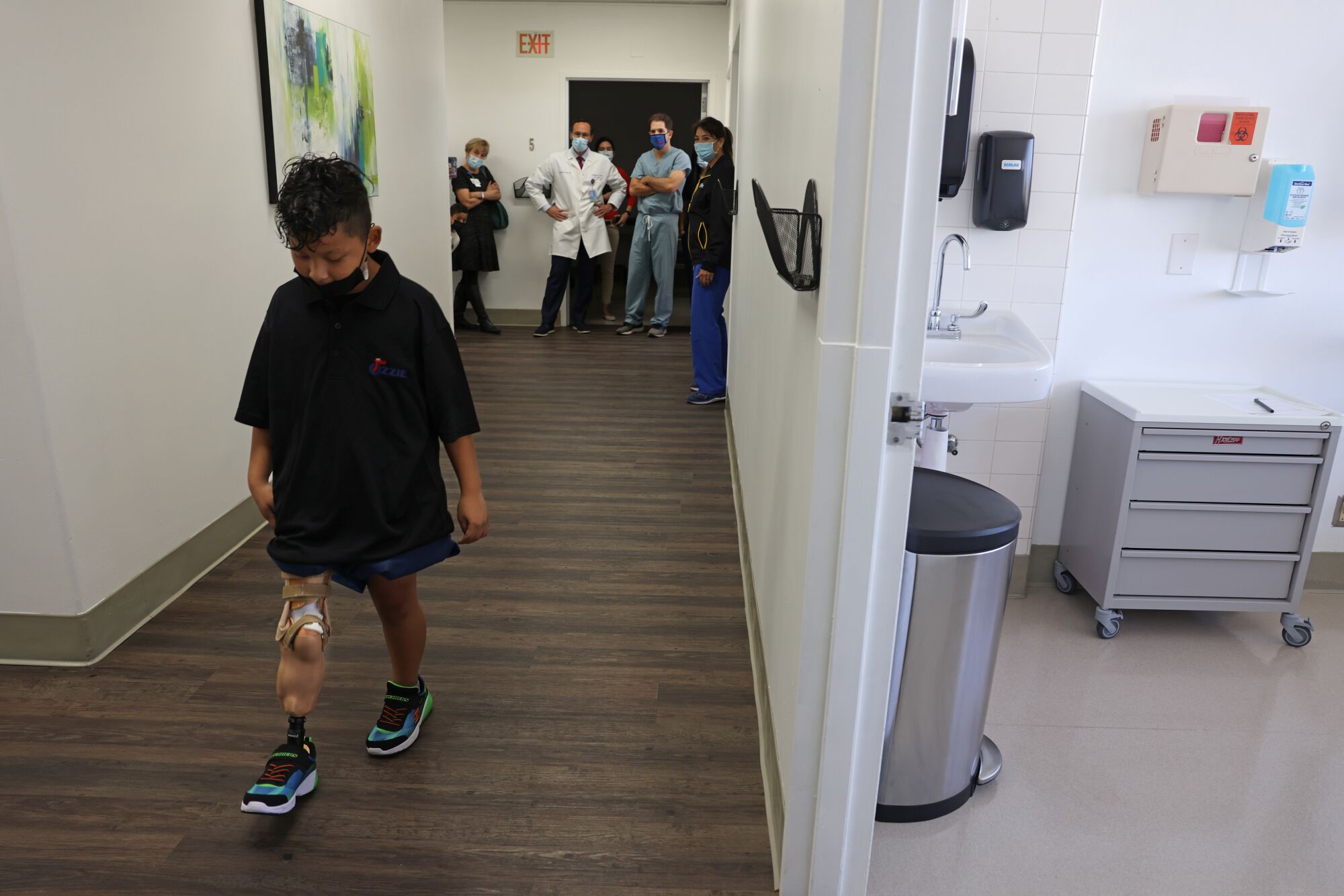 Medical staff looks on as Efraín walks with his prothesis
