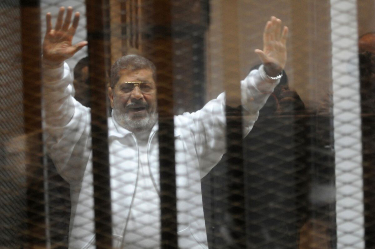 Ousted President Mohamed Morsi waves from the defendants' cage during his January trial at the police academy in Cairo.