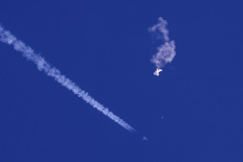 In this photo provided by Chad Fish, the remnants of a large balloon drift above the Atlantic Ocean, just off the coast of South Carolina, with a fighter jet and its contrail seen below it, Feb. 4, 2023. China on Thursday, Feb. 9, 2023, said U.S. accusations that a downed Chinese balloon was part of an extensive surveillance program amount to “information warfare against China.” (Chad Fish via AP, File)