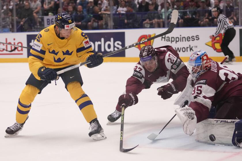 Latvia's Eriks Vitols, right, makes a save in front of Sweden's Andre Burakovsky, left, during the preliminary round match between Latvia and Sweden at the Ice Hockey World Championships in Ostrava, Czech Republic, Saturday, May 18, 2024. (AP Photo/Darko Vojinovic)