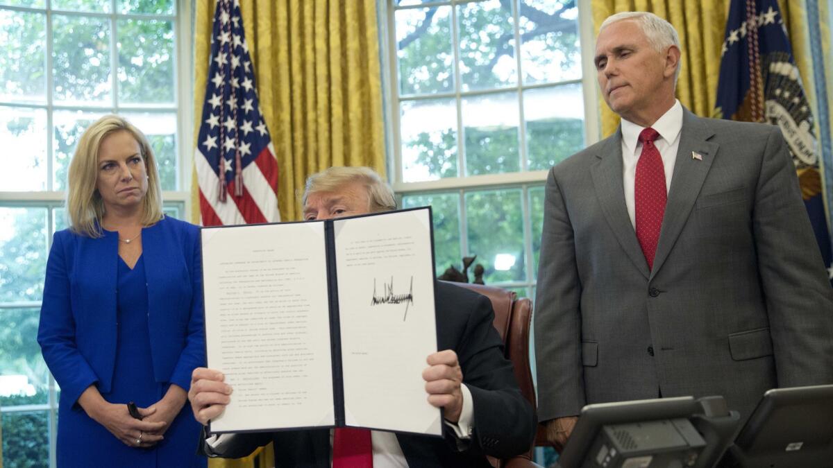 President Donald Trump holds up an executive order he signed to end family separations at the border.