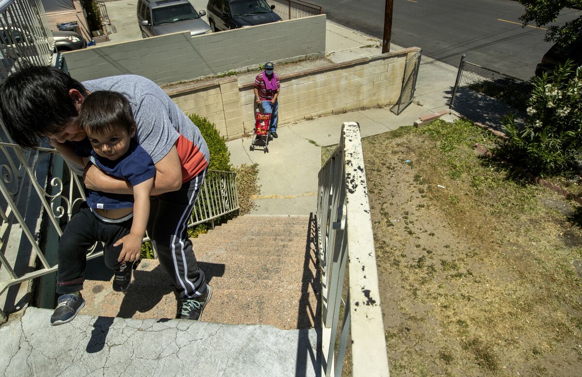 Benita Pérez le enseña a su nieto, Nevaeh Pérez, de 1 año, cómo caminar en su edificio de apartamentos en Lincoln Heights. 