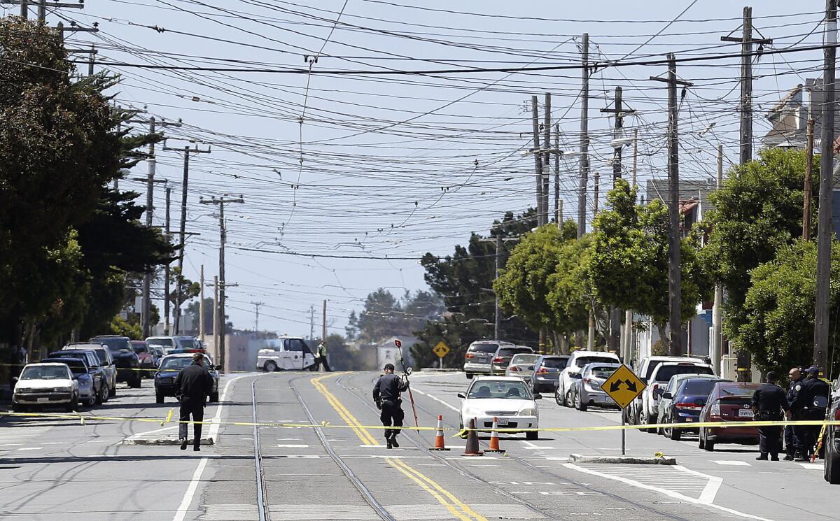 San Francisco police officers walk along San Jose Avenue, where a boy was struck and killed by a light-rail train in San Francisco.