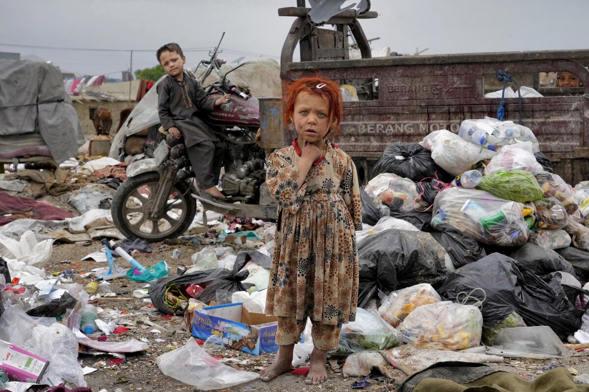 Dos niños parados entre basura junto a su casa en Kabul, Afganistán, el lunes 18 de abril de 2022. 