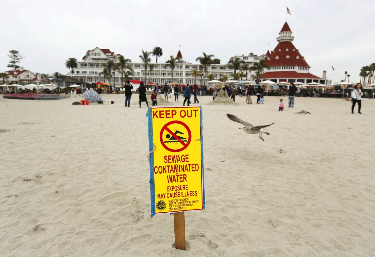 Signs warn beachgoers to avoid contact with ocean water after recent rains elevated bacteria levels in Coronado, and surrounding beaches on Dec. 29, 2019.  The Hotel del Coronado is in the background. 