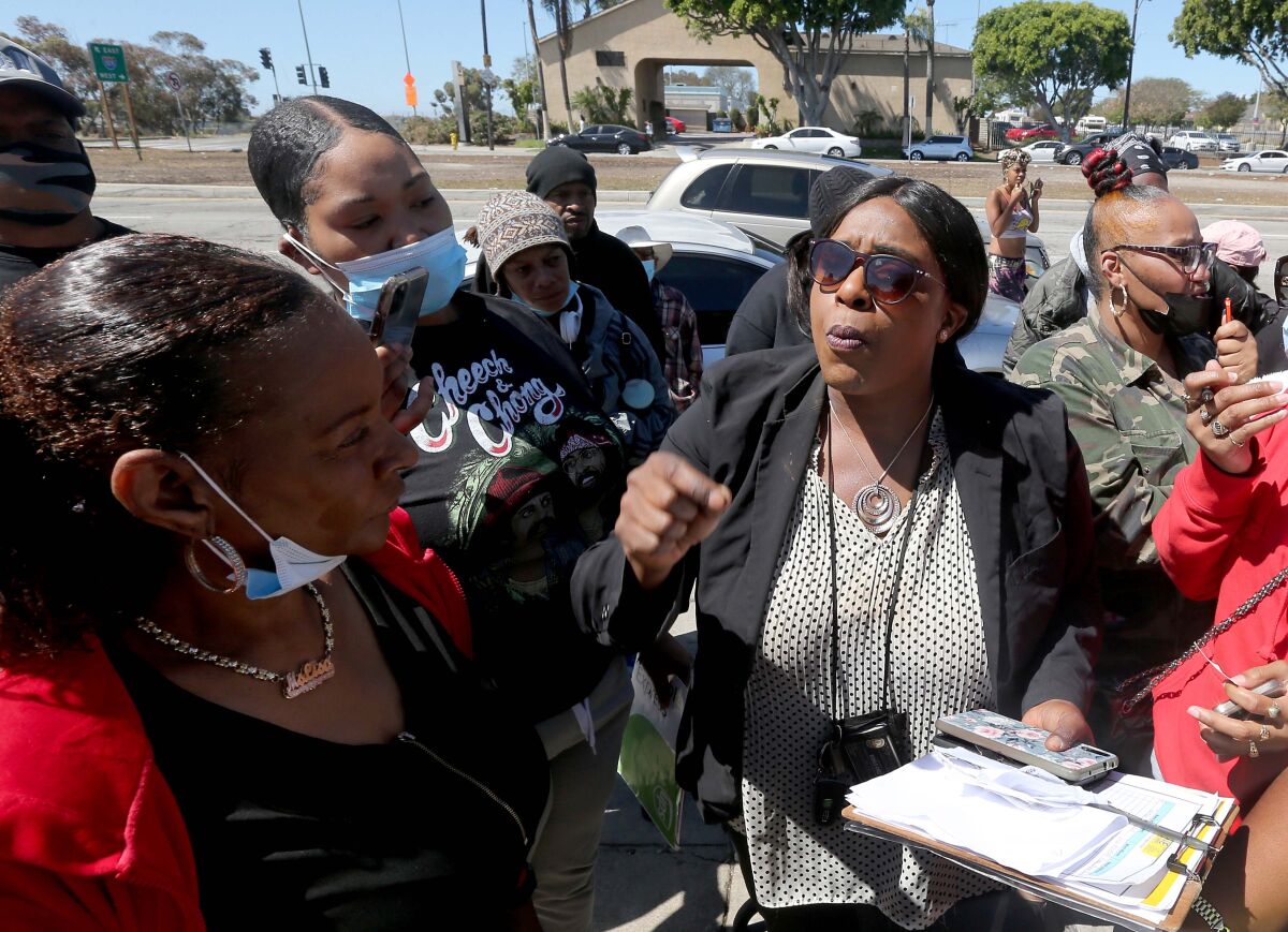 A woman with a clipboard talks to a small crowd of people.