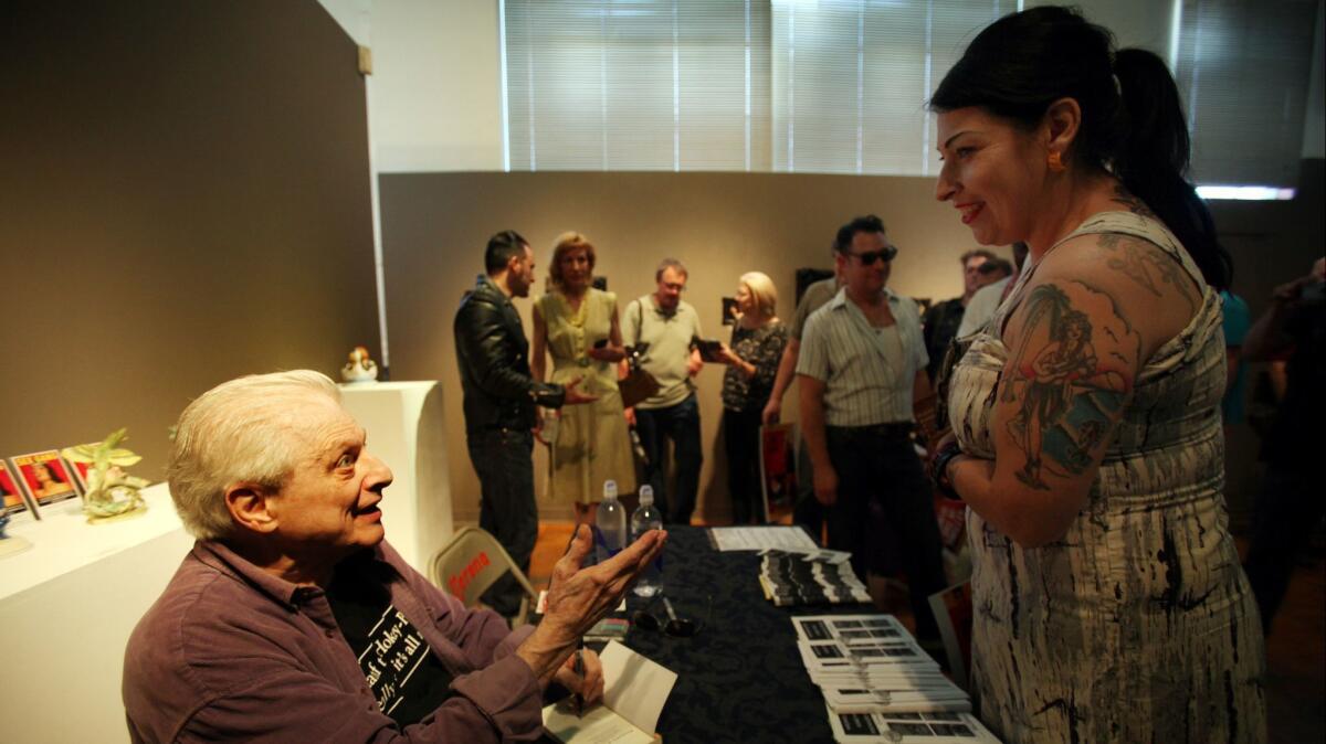 Writer Harlan Ellison, left, speaks with his fans at La Luz de Jesus Gallery during his book signing in Los Angeles in 2013. Ellison has died at age 84.