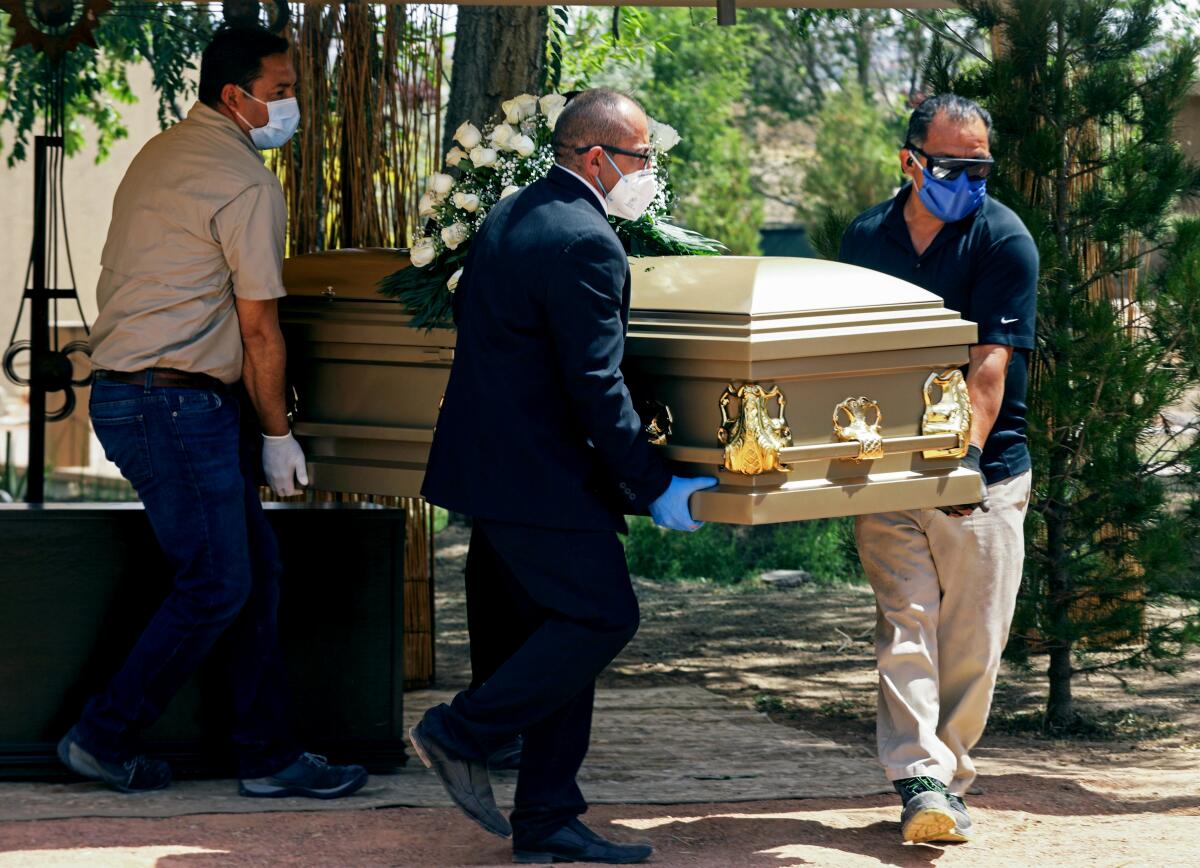 Los trabajadores de una funeraria transportan el cuerpo de una víctima de COVID-19 en Ciudad Juárez, México.