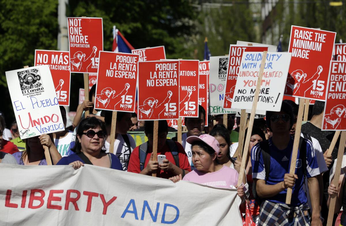 Hundreds of demonstrators walk toward downtown Seattle during a May Day march, some carrying signs in support of a boost in the minimum wage.