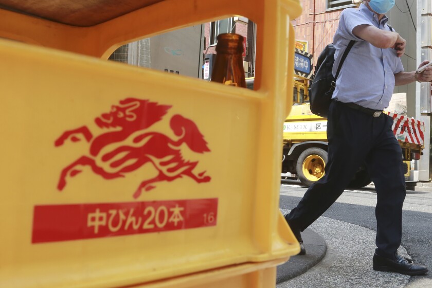 FILE - A man walks past a case of beer with a logo for Kirin brand beer in Tokyo on Aug. 25, 2020. Japanese beverage giant Kirin Holdings said Monday, Dec. 6, 2021 it is seeking commercial arbitration in a dispute over unwinding its joint venture brewery in Myanmar. (AP Photo/Koji Sasahara, File)