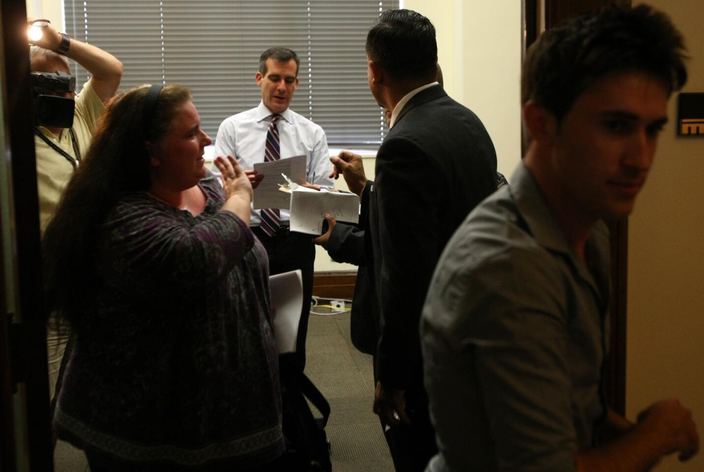 Los Angeles Mayor Eric Garcetti looks to see who his next appointment is after meeting with constituents Amanda Alonso, left, and Michael Konowitz, right. They visited the mayor at his City Hall office to discuss the benefits of the ride-sharing service Lyft.