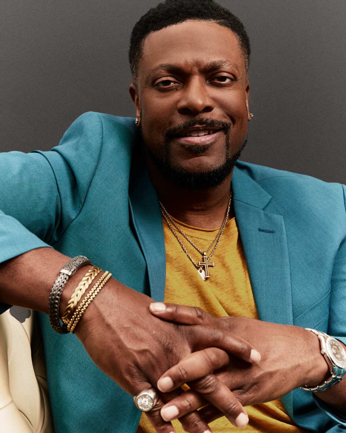 Chris Tucker smiles while leaning his arm on a seat