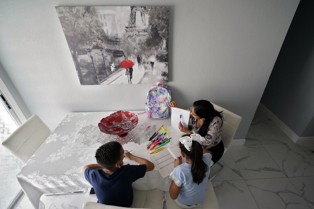 The mother of two, right, helps her children with their homework at their home Tuesday, April 19, 2022, in Tampa, Fla. More immigrants from Cuba are coming to the U.S. by making their way to Mexico and crossing the border illegally. It’s a very different reality from years ago, when Cubans enjoyed special protections that other immigrants did not have. (AP Photo/Chris O'Meara)