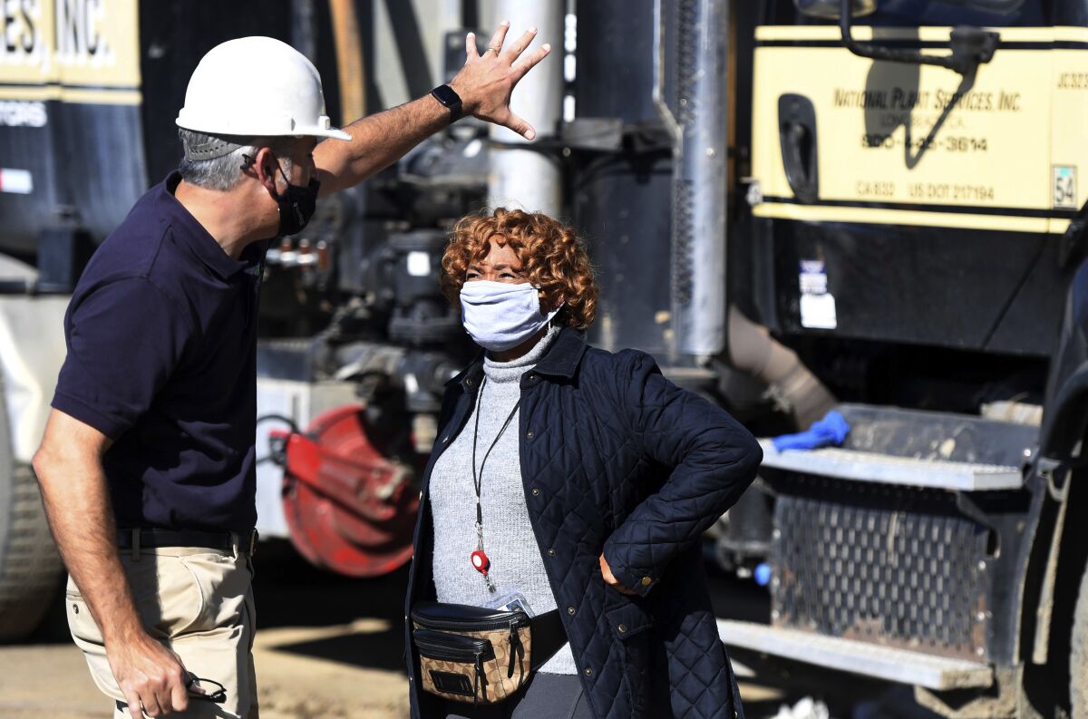 Chief engineer for sanitation districts of Los Angeles County, Robert Ferrante, gives Carson Mayor Lula Davis-Holmes a tour of the work being done on broken pipe hat caused the sewage spill this past week in Carson, Calif., on Monday, Jan. 3, 2022. Temporary pipes are pumping the sewage in a detoured route of about 1,000 feet while repairs are made on the line. (Brittany Murray/The Orange County Register via AP)