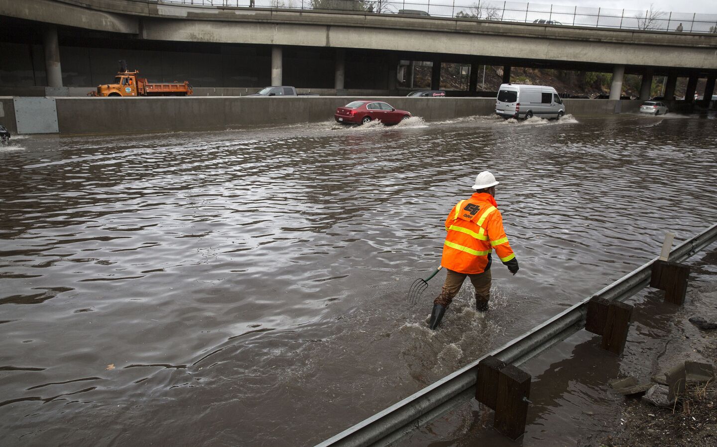 A Caltrans worker toils to clear drains on a flooded Interstate 5 in Sun Valley, Calif.