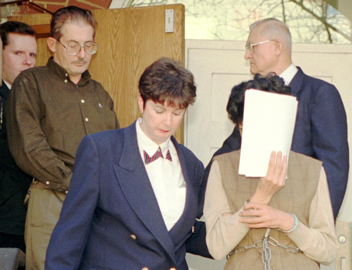 Maria del Rosario Casas Ames, with face covered, and her husband, Aldrich Ames, upper left, leave a federal courthouse in 1994. He is serving a life sentence for espionage. She was sentenced to five years in prison for conspiring to commit espionage and tax evasion.