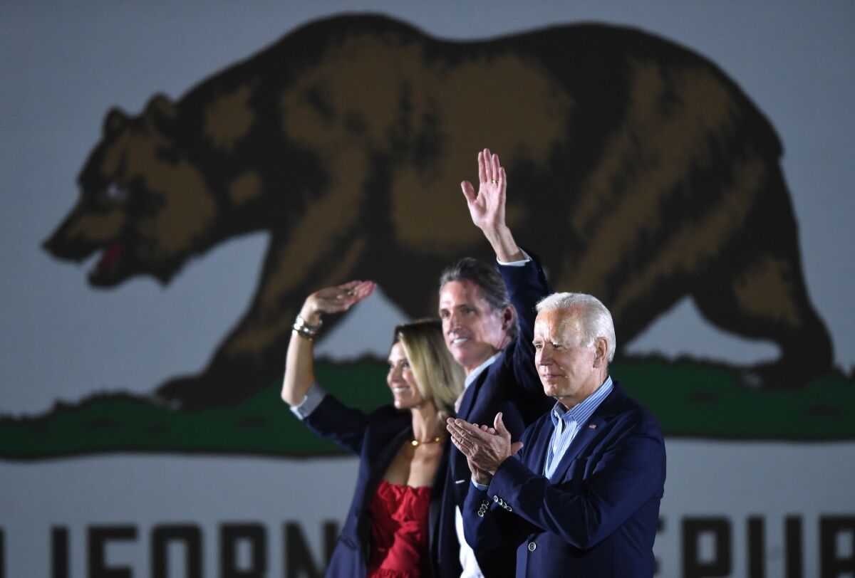Gov. Gavin Newson waves while campaigning with wife Jennifer Siebel Newsom and President Biden