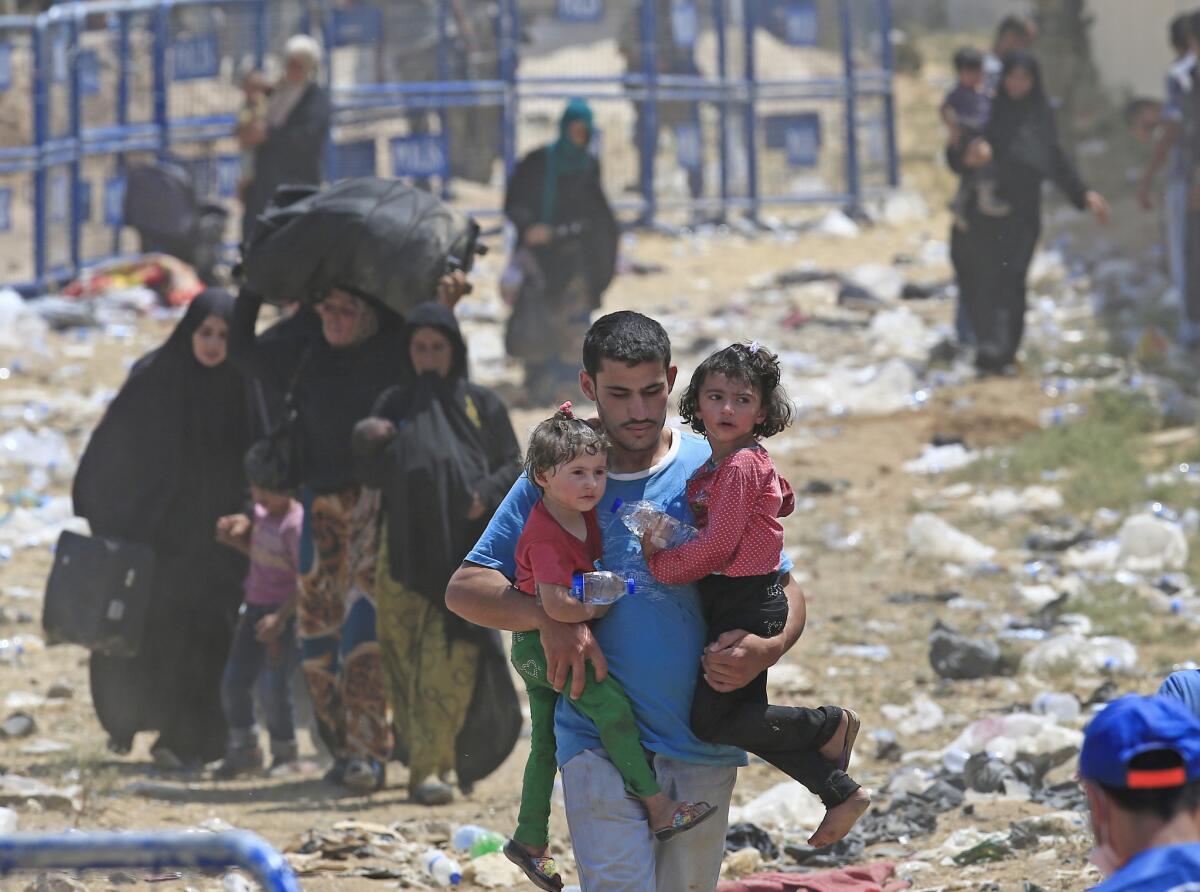 Un refugiado sirio lleva a dos niños en Akcakale, sureste de Turqií adonde han llegada oleadas de personas que escapan de los duros combates enrtre milicias curdas y extremistas del grupo Estado Islámico el lunes 15 de junio de 2015.