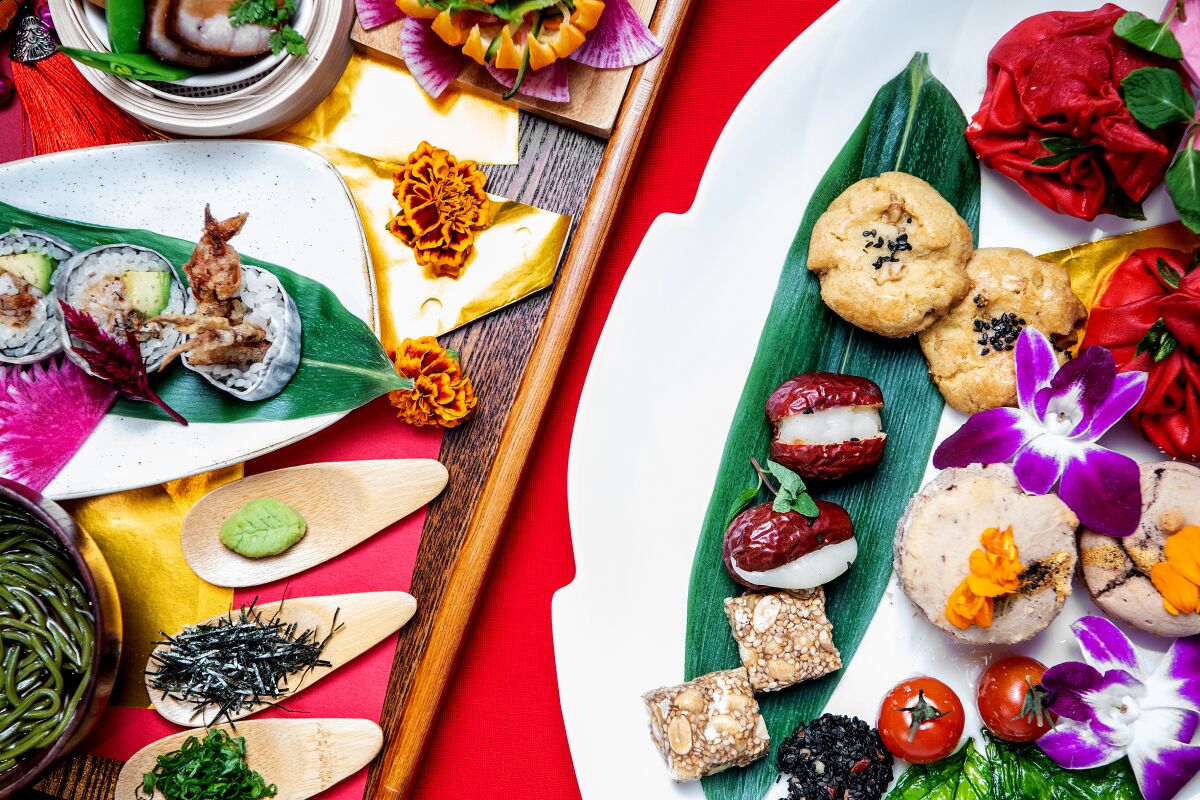 An overhead photo of brightly colored high tea food items on platters with purple flowers throughout