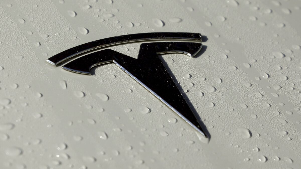 The Tesla logo on a wet car 