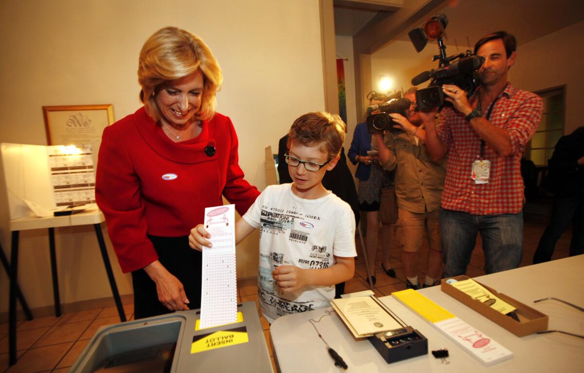 Then-L.A. mayoral candidate Wendy Greuel, left, watches as her son, 9-year-old Thomas Schramm, enters a voting ballot at the Unitarian Universalist Church in Studio City in May.