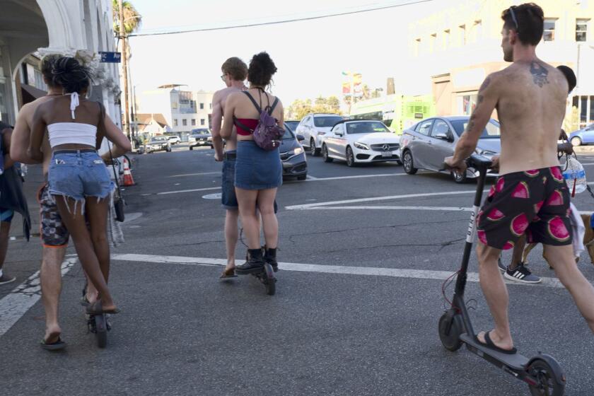 In this Tuesday, July 24, 2018 photo riders make they're way across a street on Bird electric scooters in the Venice Beach section of Los Angeles. (AP Photo/Richard Vogel)