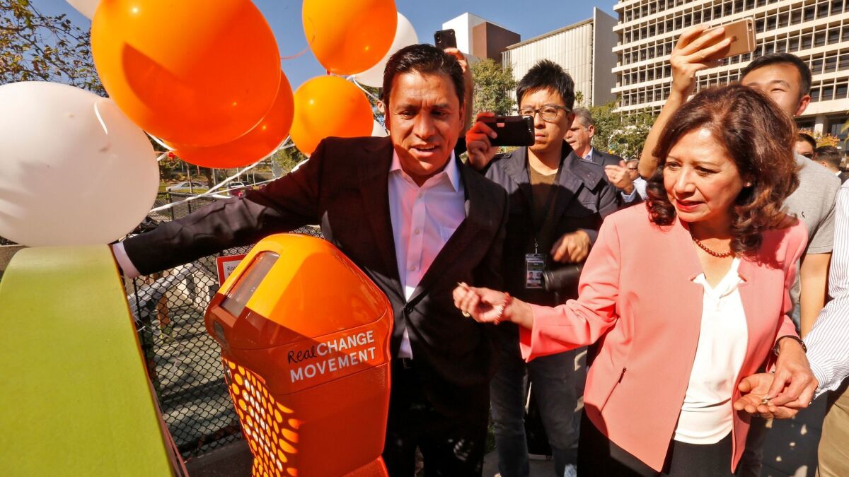 Los Angeles City Councilman Jose Huizar, left, and Los Angeles County Supervisor Hilda L. Solis put money into a homeless donation meter in downtown L.A.'s Grand Park on Thursday.