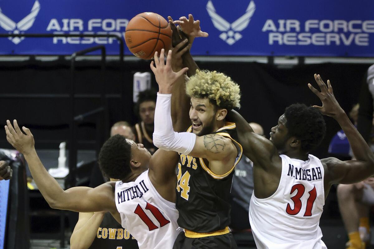 Wyoming guard Hunter Maldonado (24) reaches for a rebound with San Diego State forward Matt Mitchell (11) and forward Nathan Mensah (31) during the first half of an NCAA college basketball game in the quarterfinal round of the Mountain West Conference tournament Thursday, March 11, 2021, in Las Vegas. (AP Photo/Isaac Brekken)