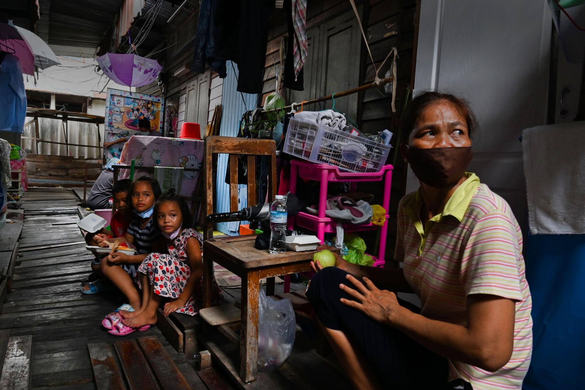 A woman holds a piece of fruit distributed as a part of a food donation package in a low-income neighborhood in Bangkok.