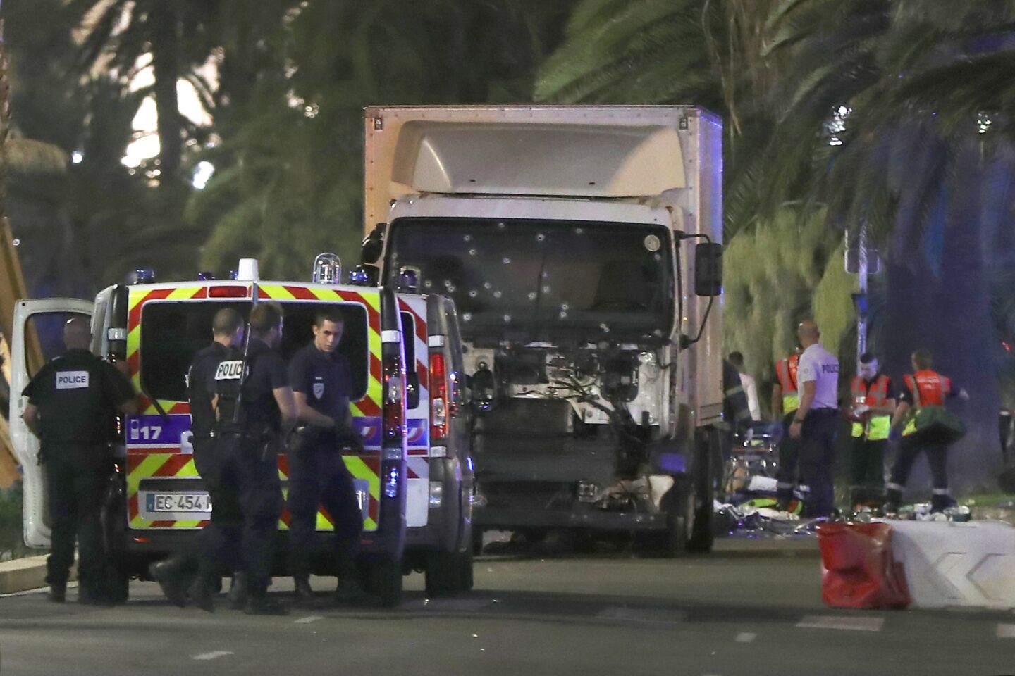Police officers and rescue workers stand near a truck that plowed into a crowd of people leaving a fireworks display in the French Riviera town of Nice on Bastille Day. Dozens of revelers were killed.