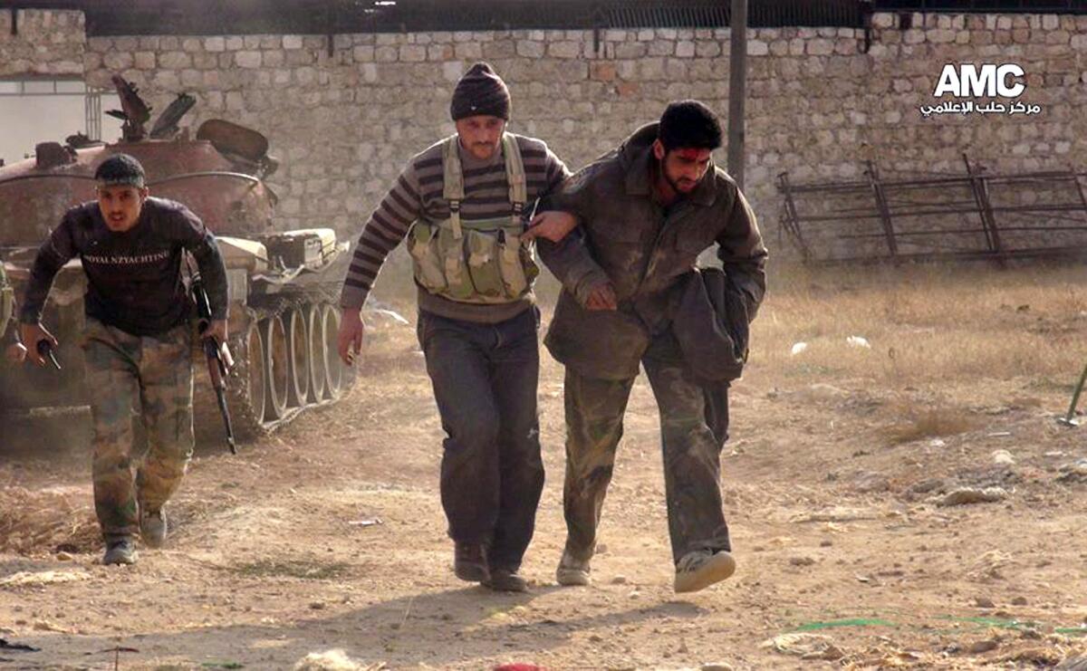 Two Free Syrian Army fighters help a wounded comrade during clashes in Aleppo, Syria.
