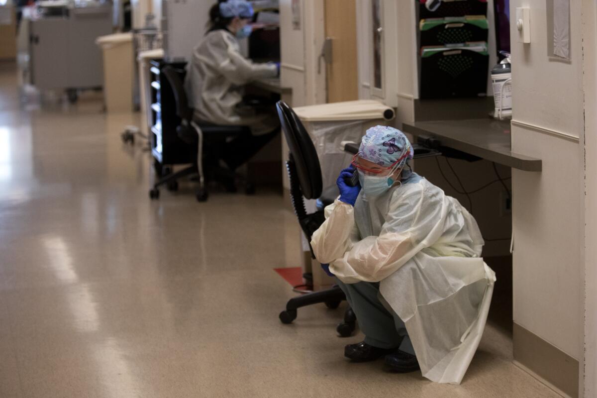 A nurse crouches in a hallway