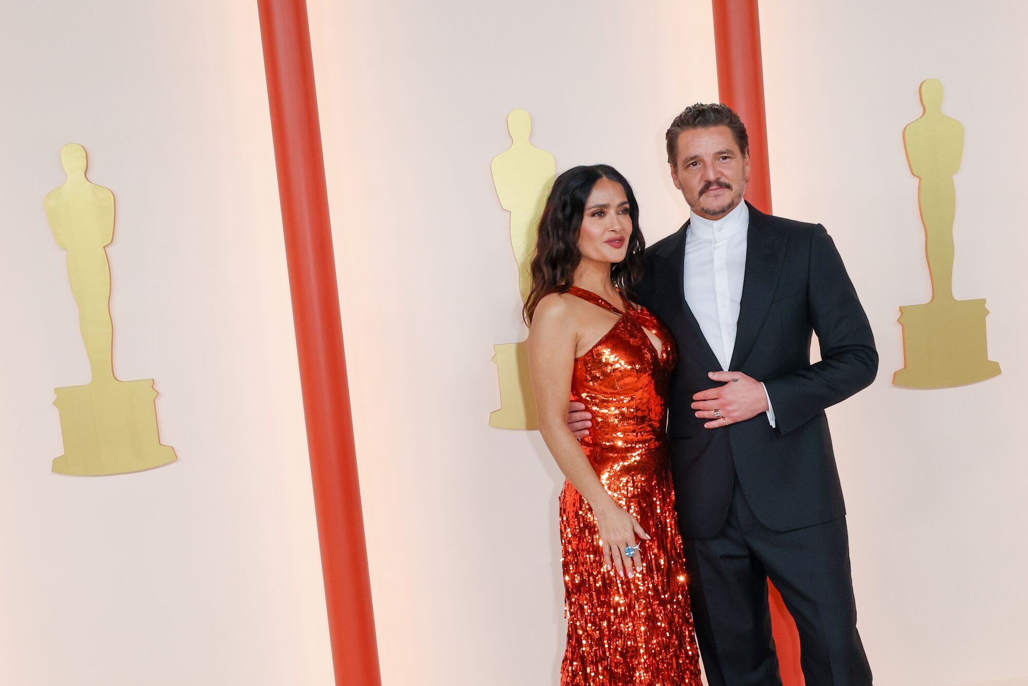 Pedro Pascal in black tuxedo and Salma Hayek a sparkling red gown.
