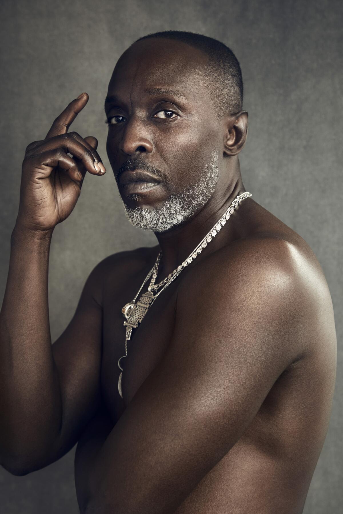 Michael K. Williams, photographed shirtless, in partial profile, looking directly at the camera. 