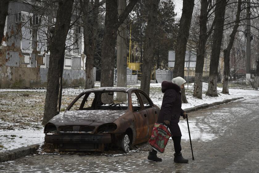 A local resident walks past a burnt car that was damaged in Russian shelling in the town of Orekhovo, Zaporizhzhya region, Ukraine, Monday, Jan. 30, 2023. (AP Photo/Andriy Andriyenko)
