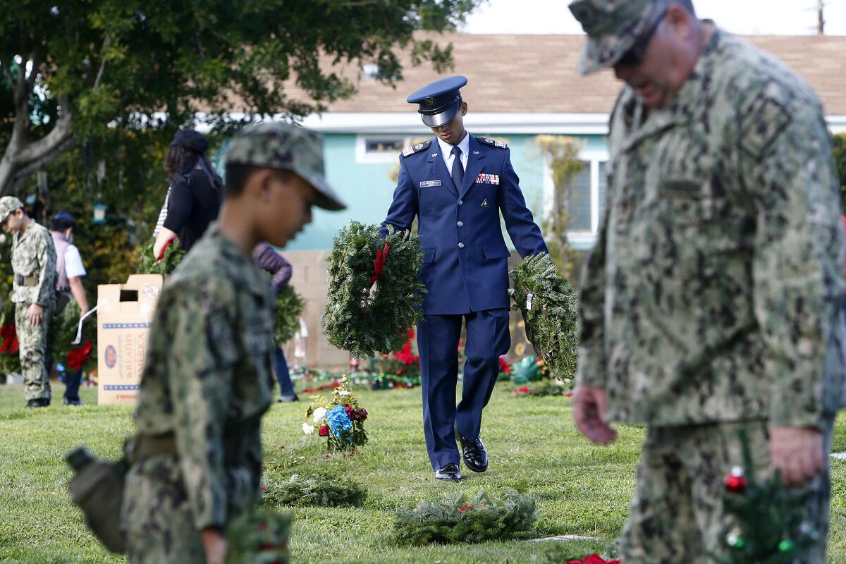 U.S. military personnel help place wreaths atop tombstones at Memory Gardens Cemetery in Brea.