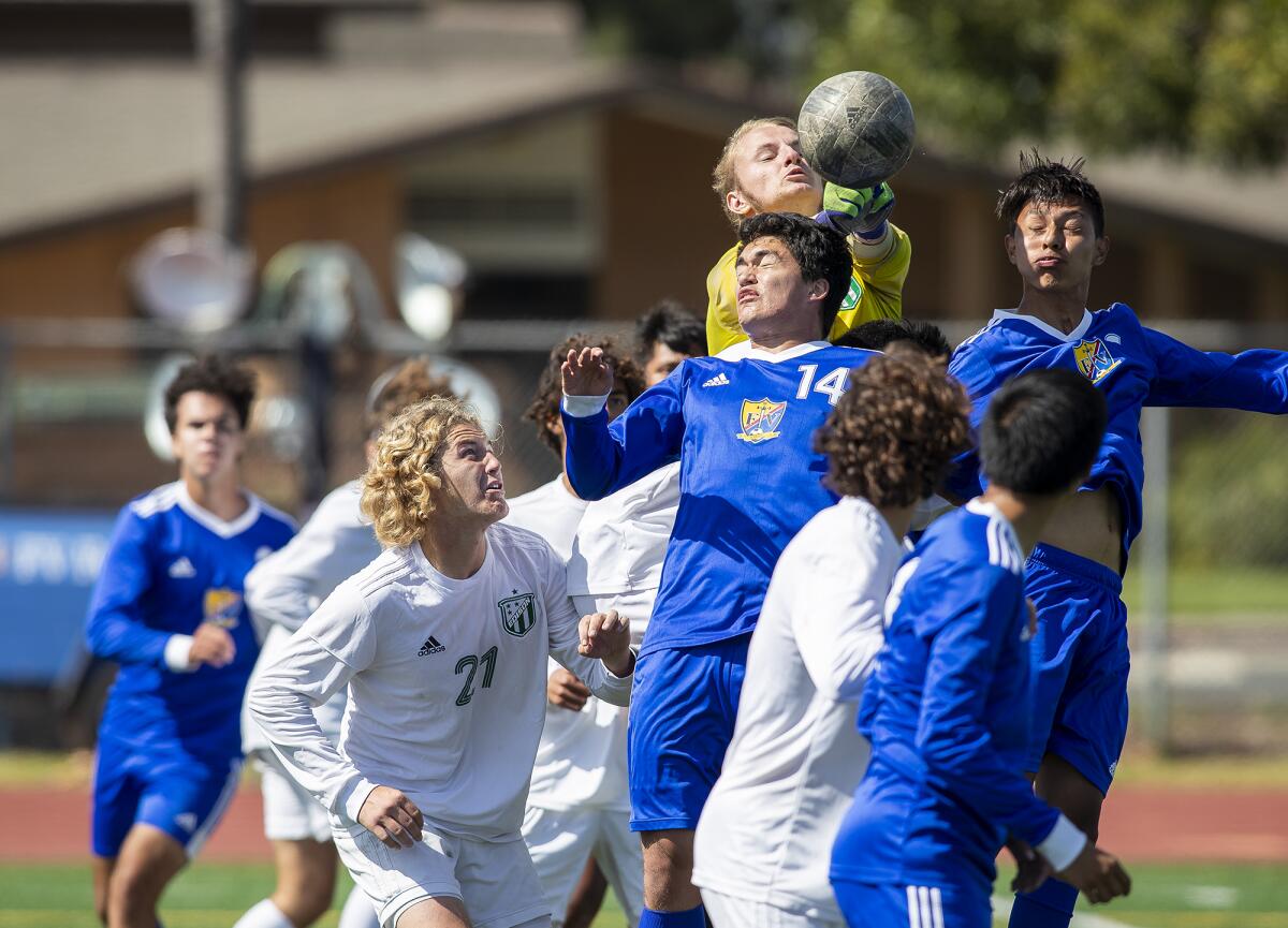 Edison goalie Bennett Flory goes up for a ball against Fountain Valley's Johnathan Swete, center, and Alan Villegas.