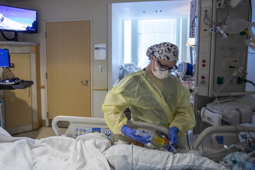 TORRANCE, CA - JANUARY 11: Registered nurse Anh Bui, is working with a Covid19 positive patient in the ICU at Providence Little Company of Mary Medical Center on Tuesday, Jan. 11, 2022 in Torrance, CA. (Francine Orr / Los Angeles Times)