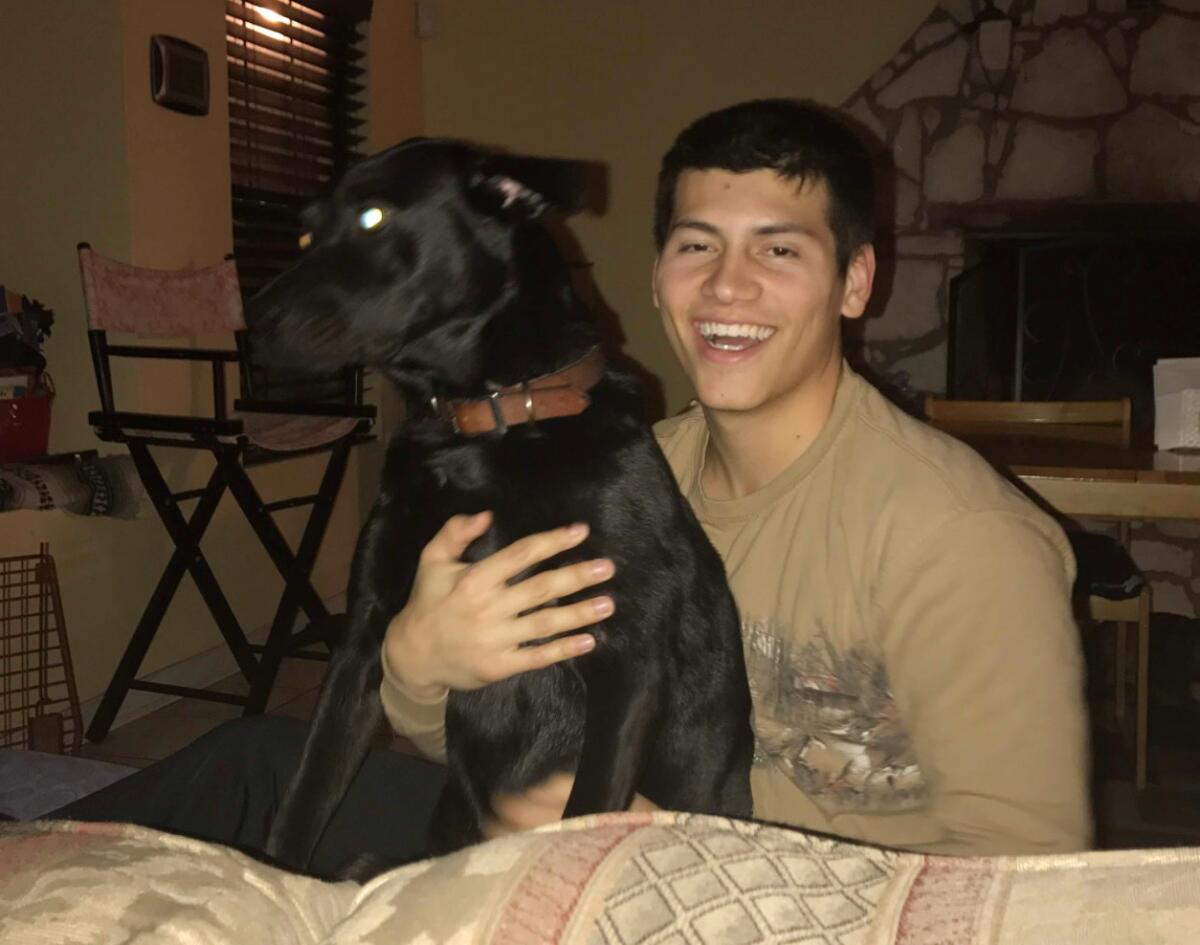 Rodriguez holds his black dog and smiles.
