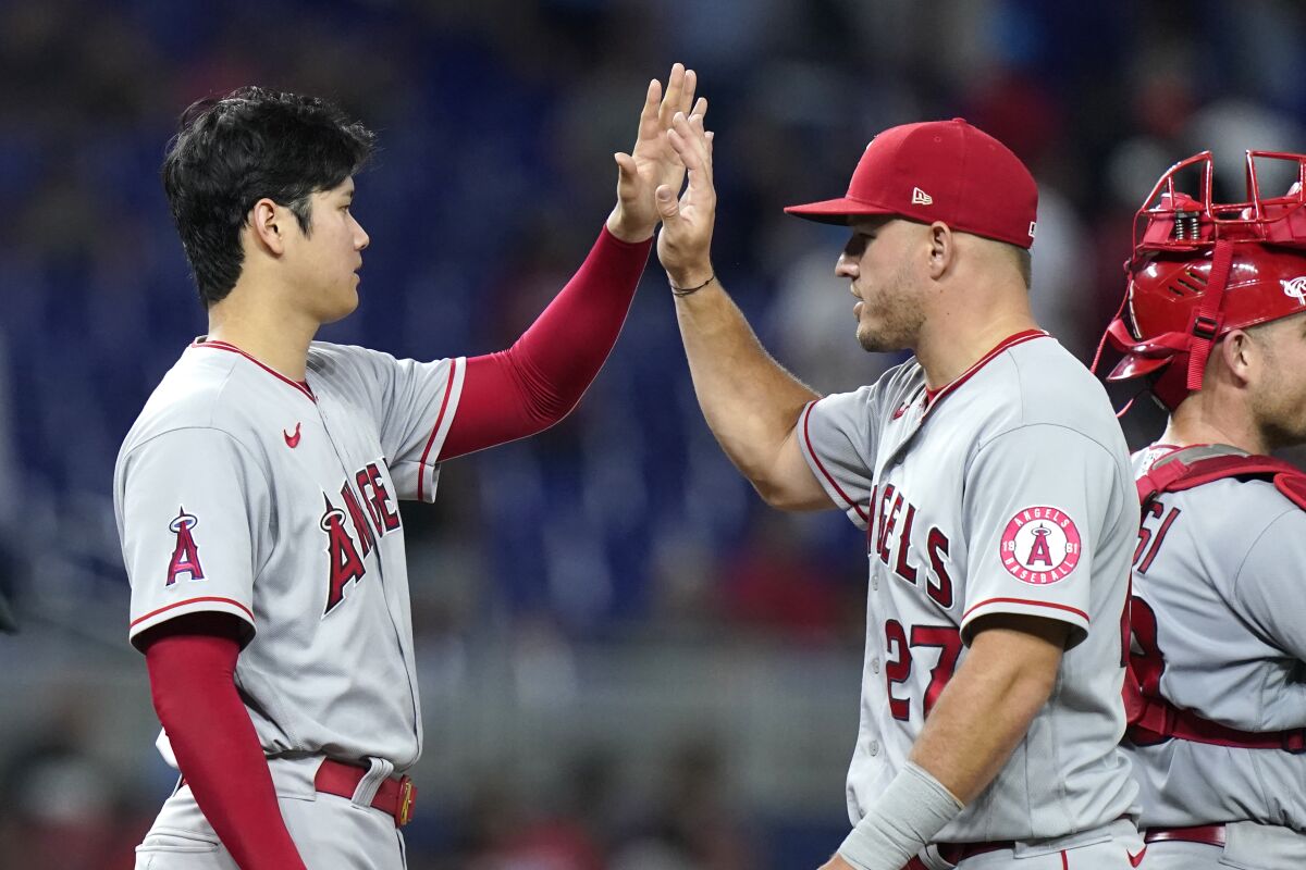 Angels pitcher Shohei Ohtani high-fives center fielder Mike Trout after defeating the Miami Marlins on July 6, 2022.